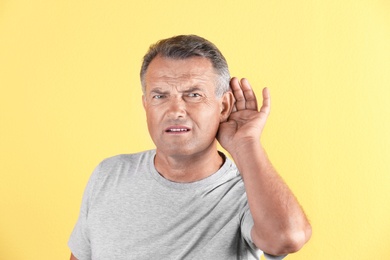 Photo of Mature man with hearing problem on color background