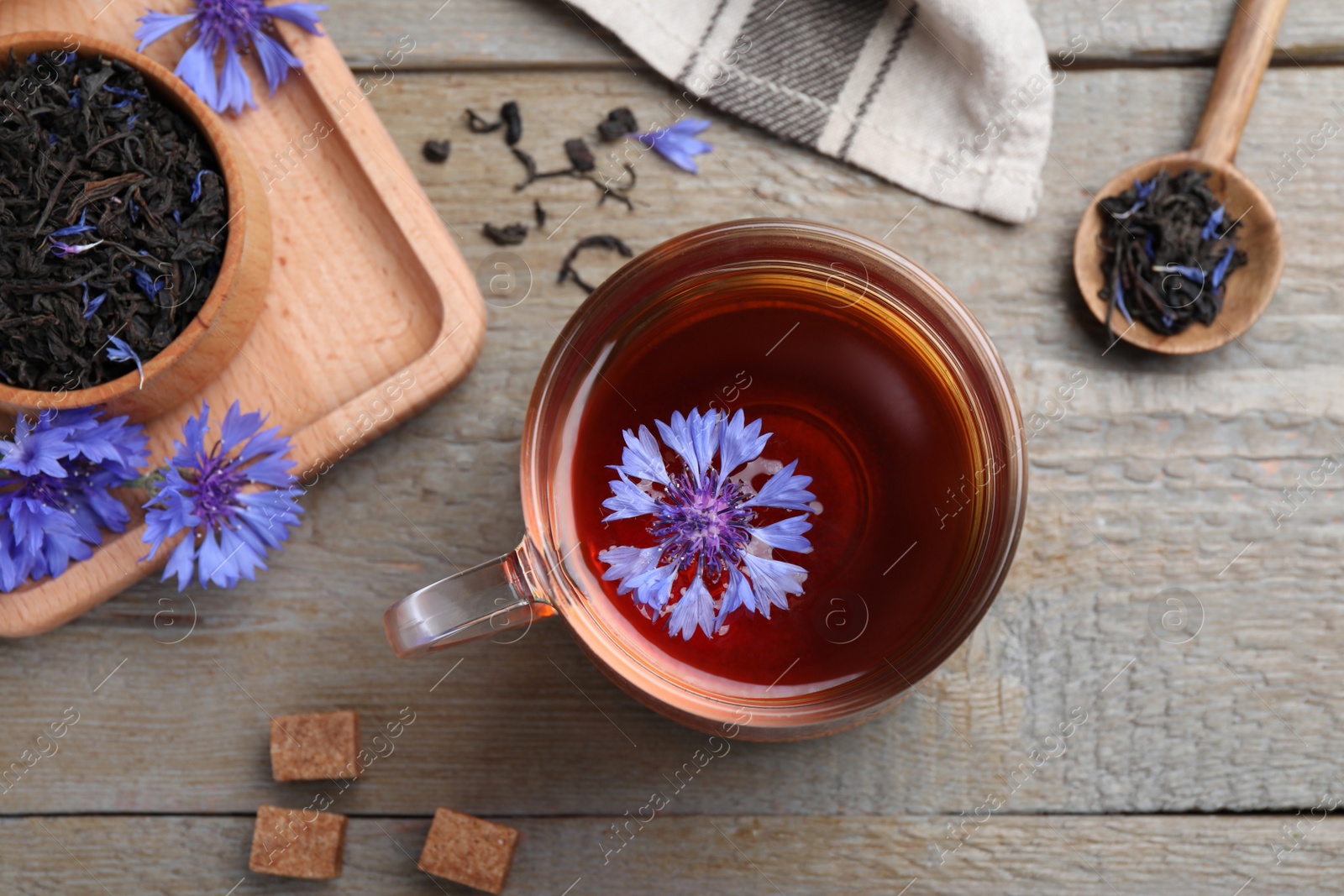 Photo of Flat lay composition with tea and cornflowers on wooden table