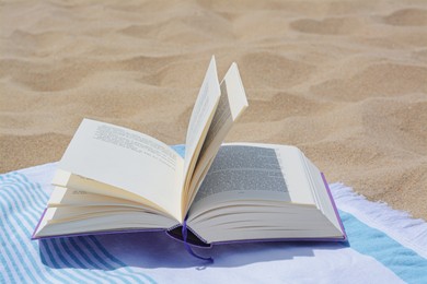 Photo of Beach towel with open book on sand