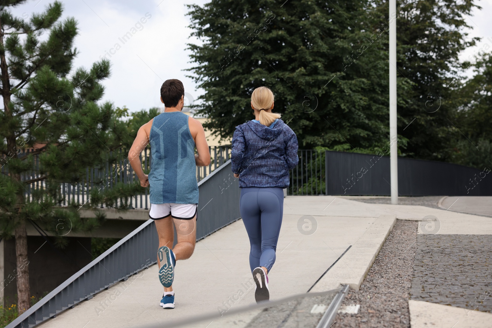 Photo of Healthy lifestyle. Sporty couple running outdoors, back view. Space for text