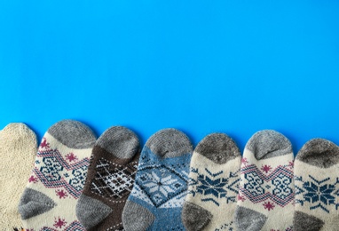 Photo of Soft knitted socks on blue background, flat lay with space for text. Winter clothes