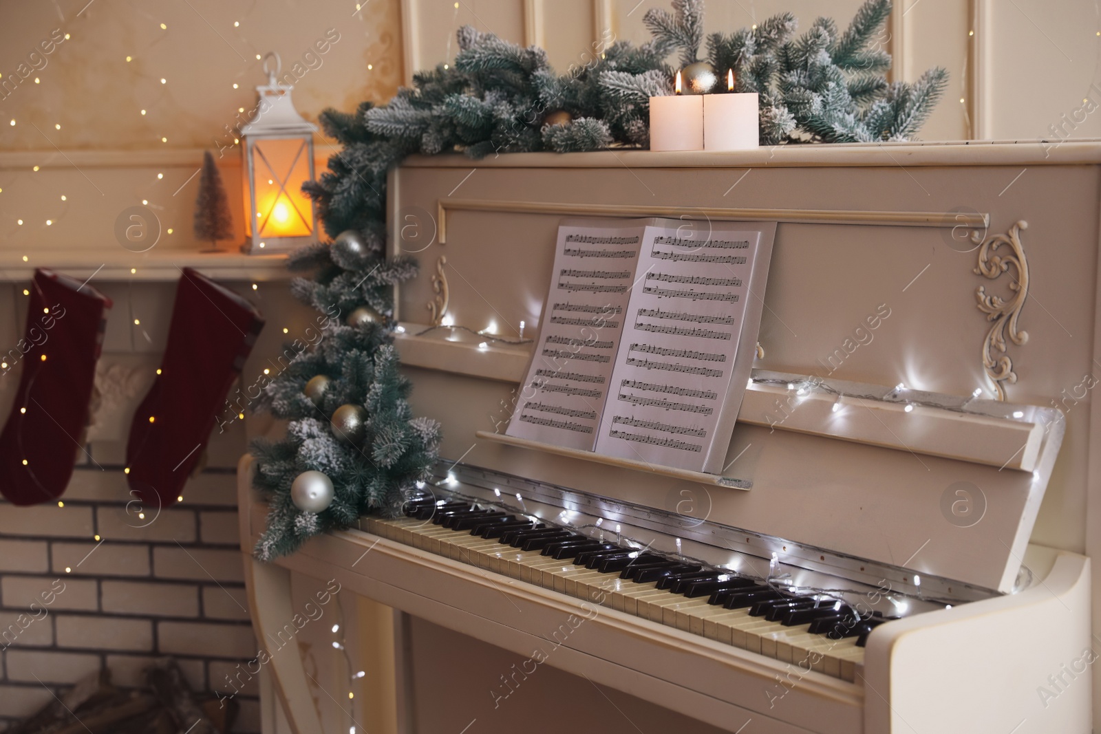 Photo of White piano with festive decor and note sheets indoors. Christmas music