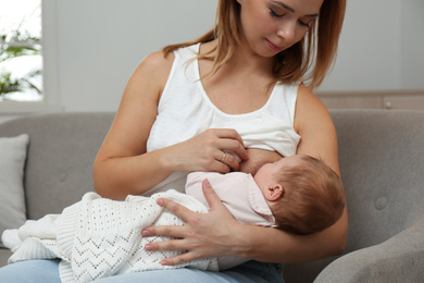 Photo of Young woman breast feeding her little baby at home