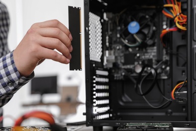 Male technician putting RAM chip into system unit, closeup. Computer repair