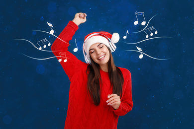 Image of Young woman in Santa hat listening to music through headphones on color background