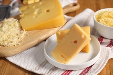 Photo of Grated and cut cheese on wooden table, closeup