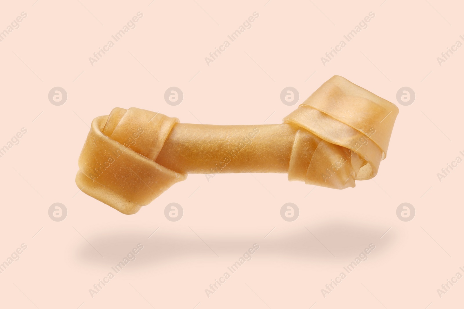 Image of Bone dog treat in air on beige pink background