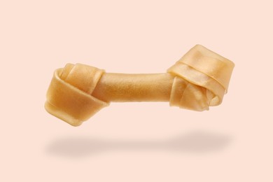 Bone dog treat in air on beige pink background