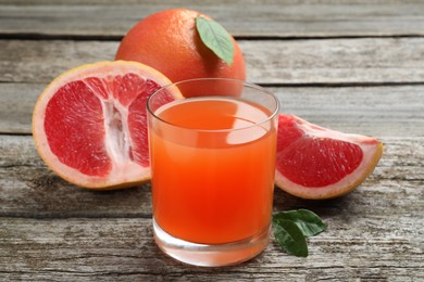 Photo of Tasty freshly made grapefruit juice and fruits on wooden table