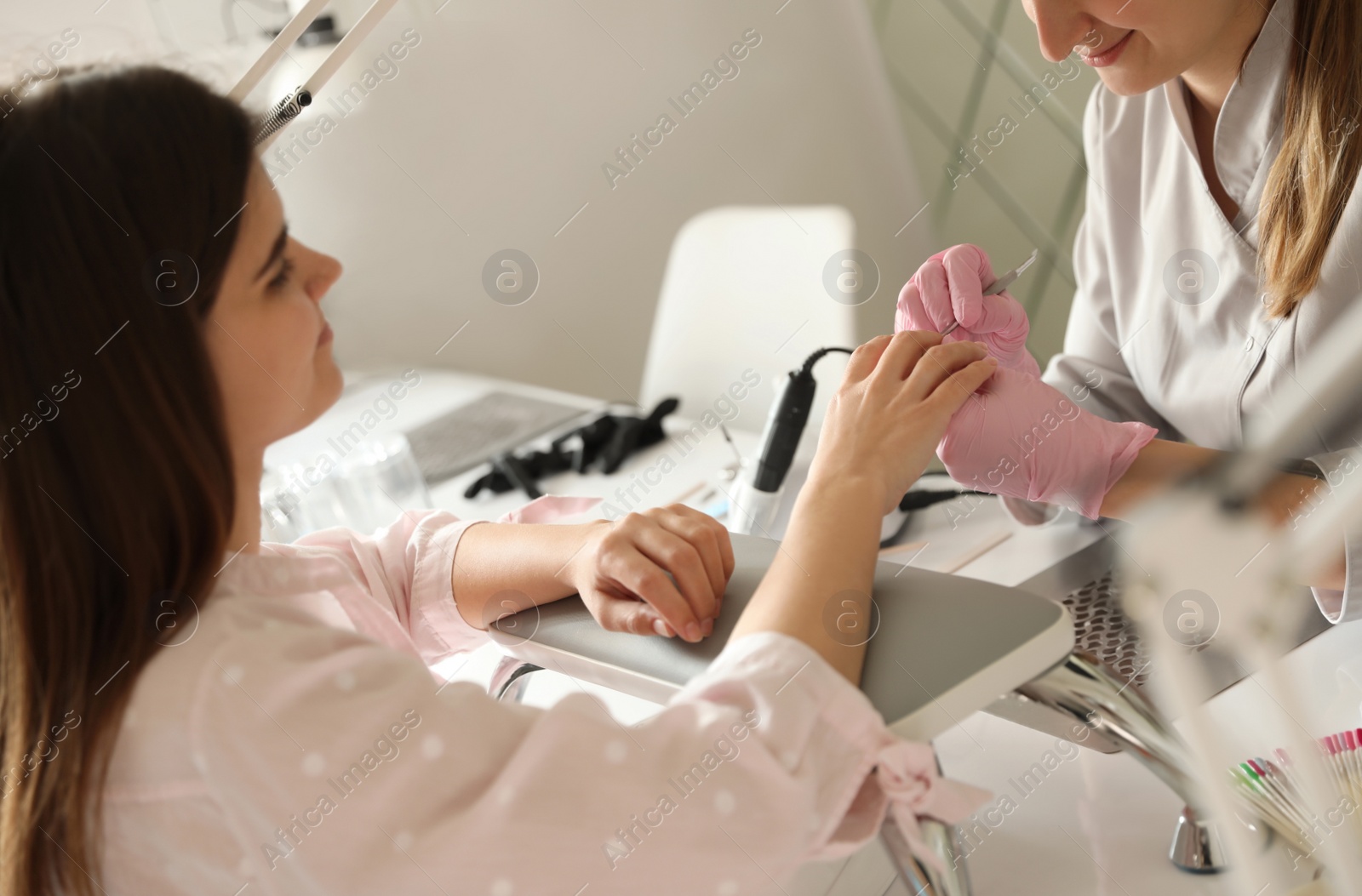 Photo of Professional manicurist working with client in beauty salon