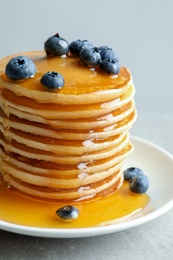 Photo of Plate with pancakes and berries on grey background, closeup