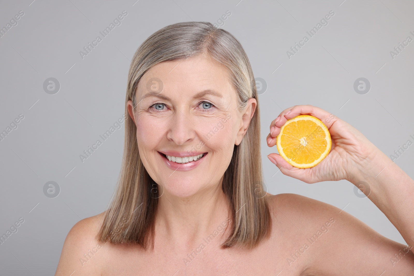 Photo of Beautiful woman with half of orange rich in vitamin C on grey background