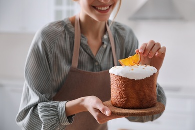 Photo of Young woman with traditional decorated Easter cake indoors, closeup