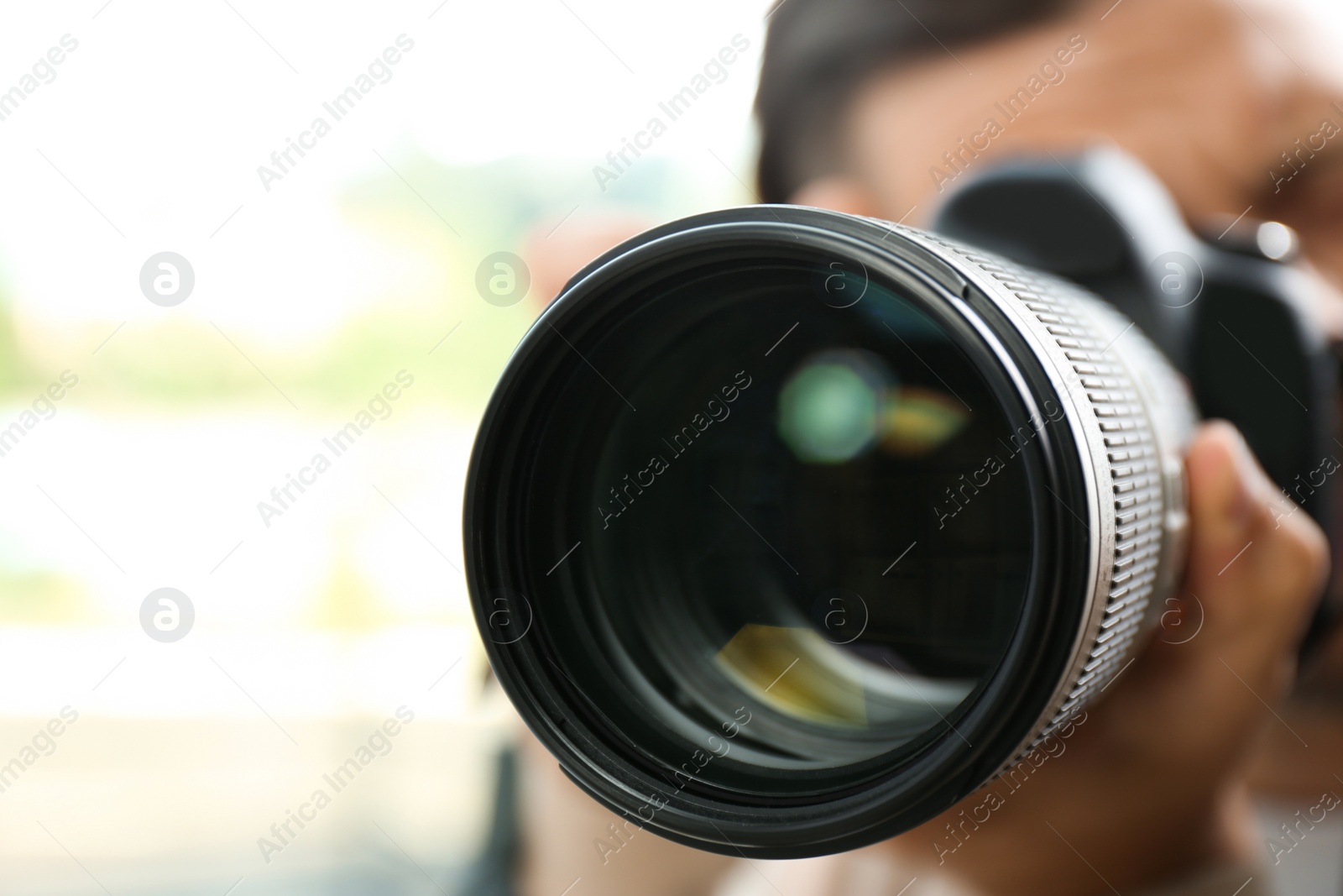 Photo of Male photographer with professional camera on blurred background, closeup