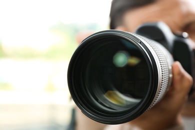 Photo of Male photographer with professional camera on blurred background, closeup