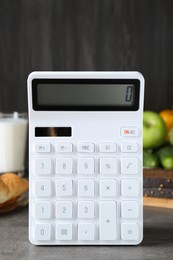 Photo of Calculator and food products on dark grey table. Weight loss concept