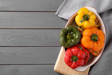 Photo of Tasty stuffed bell peppers in baking dish on grey wooden table, top view. Space for text