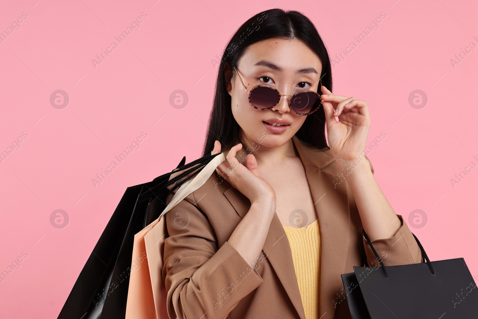 Photo of Beautiful woman with shopping bags on pink background