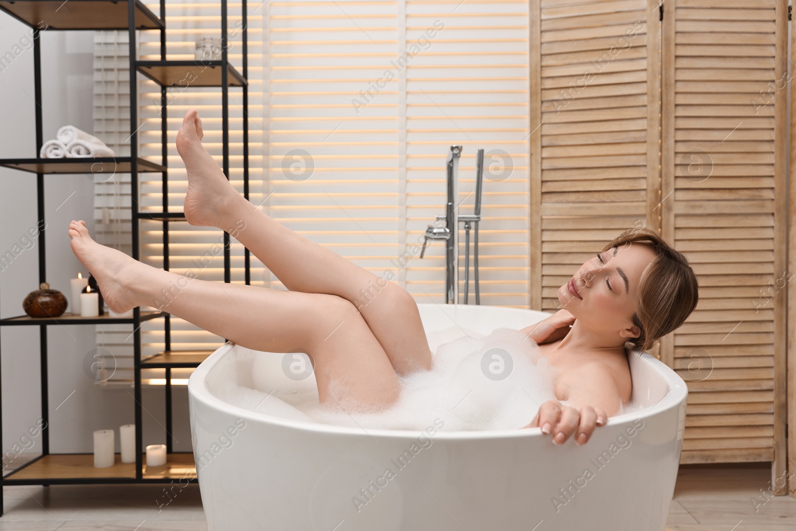 Photo of Beautiful woman taking bath with foam in tub indoors