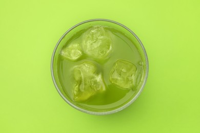 Photo of Glass of delicious iced matcha tea on green background, top view