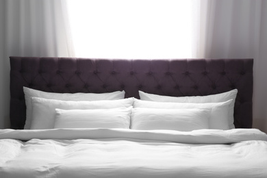 Photo of Modern bed with soft pillows near window