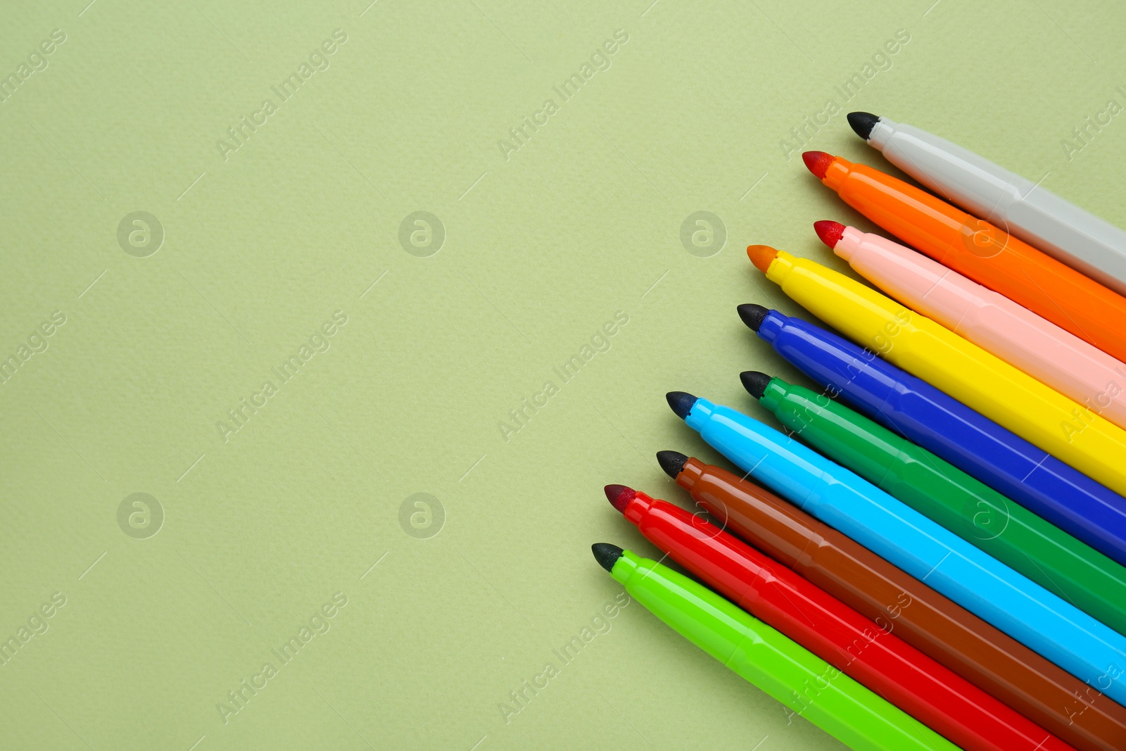 Photo of Different colorful markers on light green background, flat lay. Space for text