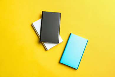 Photo of Modern external portable chargers on yellow background