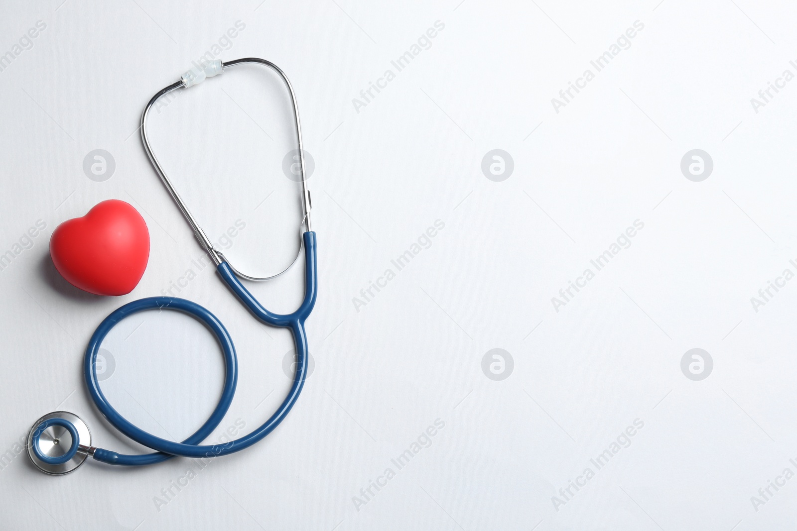 Photo of Stethoscope and red heart on white background, top view. Health insurance concept