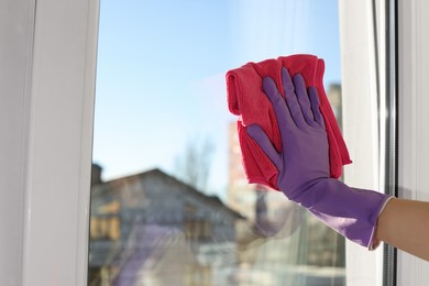 Photo of Young woman cleaning window glass with rag at home, closeup. Space for text