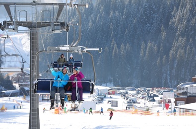 People using chairlift at mountain ski resort. Winter vacation