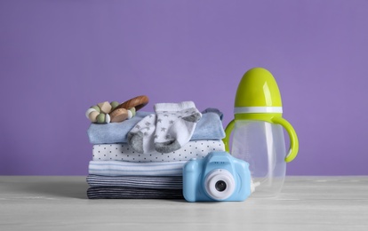 Children's accessories, toys and stack of clothes on white wooden table