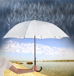 Image of Woman with open umbrella under heavy rain near river, closeup