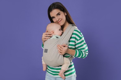 Photo of Mother holding her child in sling (baby carrier) on purple background