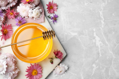 Photo of Flat lay composition with jar of organic honey and dipper on grey marble table. Space for text