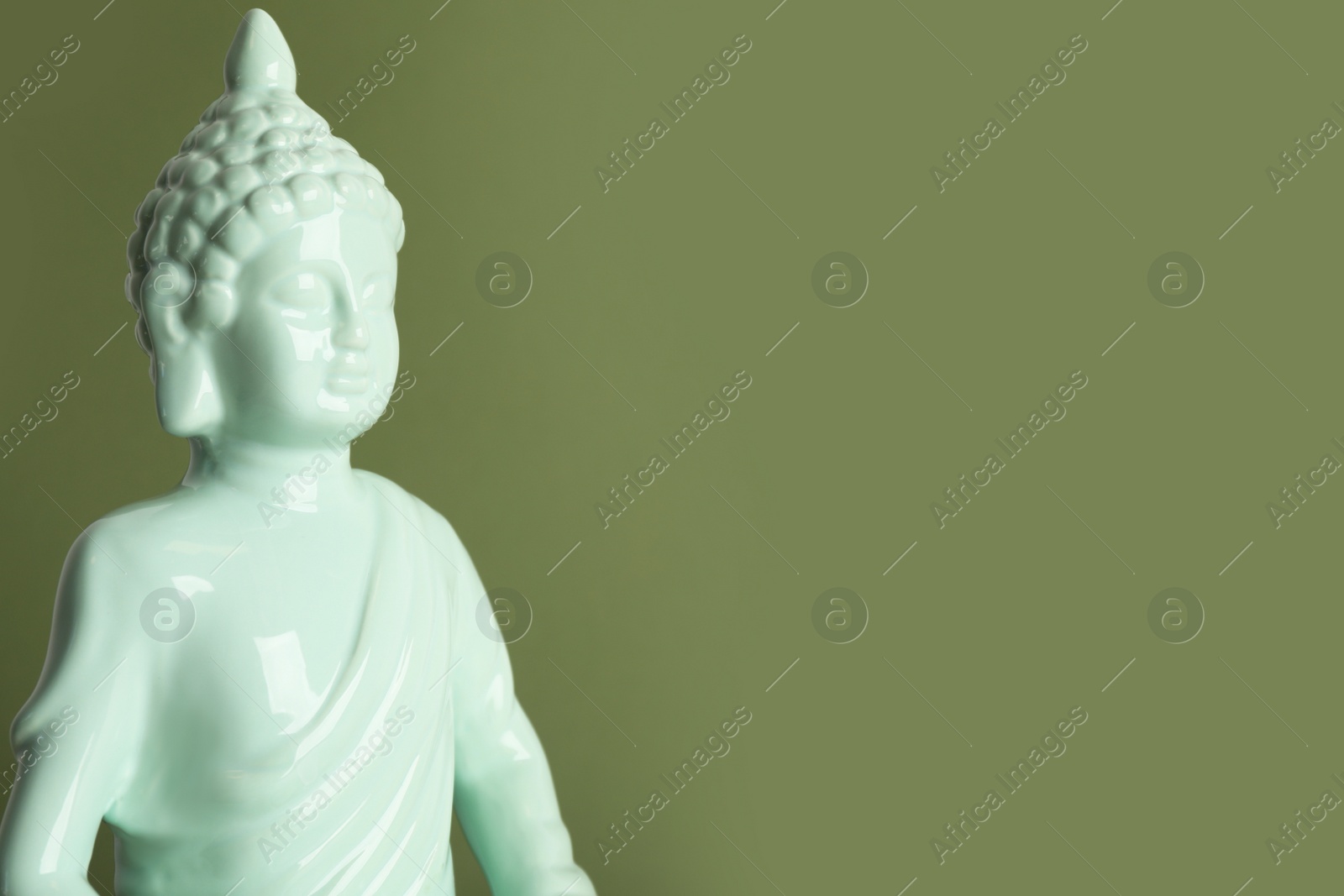 Photo of Beautiful ceramic Buddha sculpture on green background. Space for text