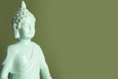 Photo of Beautiful ceramic Buddha sculpture on green background. Space for text