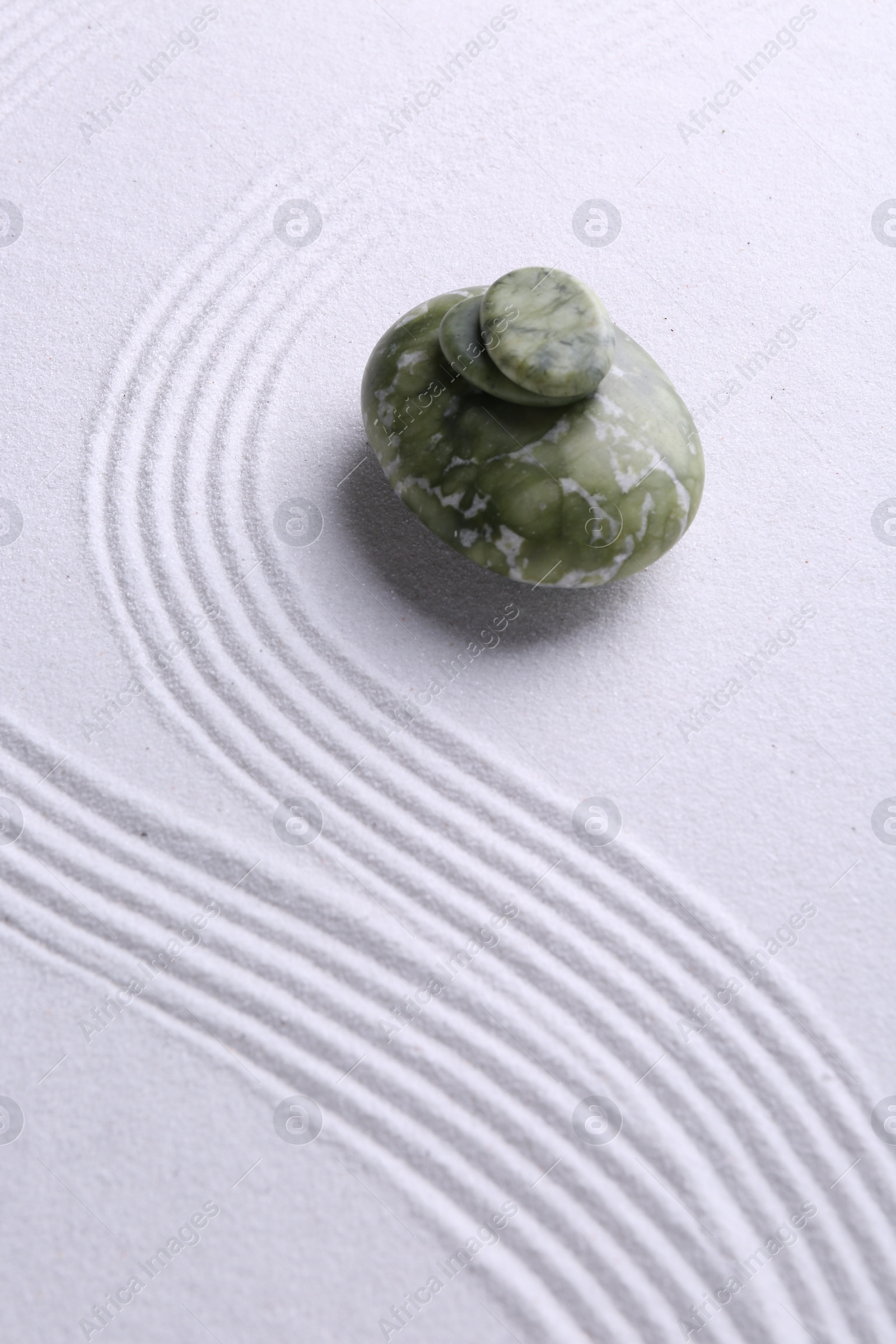 Photo of Zen garden stones on white sand with pattern. Space for text