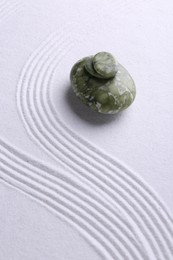 Photo of Zen garden stones on white sand with pattern. Space for text