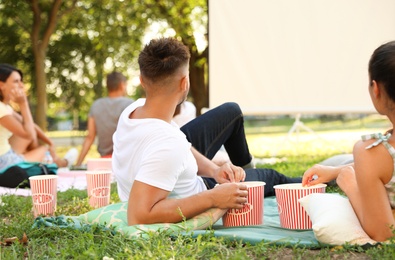 Young couple with popcorn watching movie in open air cinema. Space for text