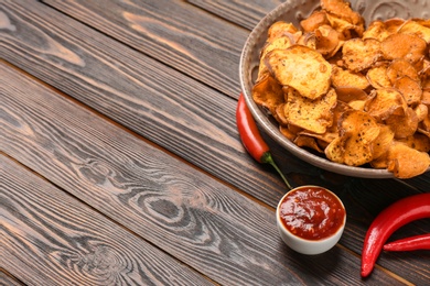 Photo of Plate of sweet potato chips, sauce and hot pepper on wooden table. Space for text