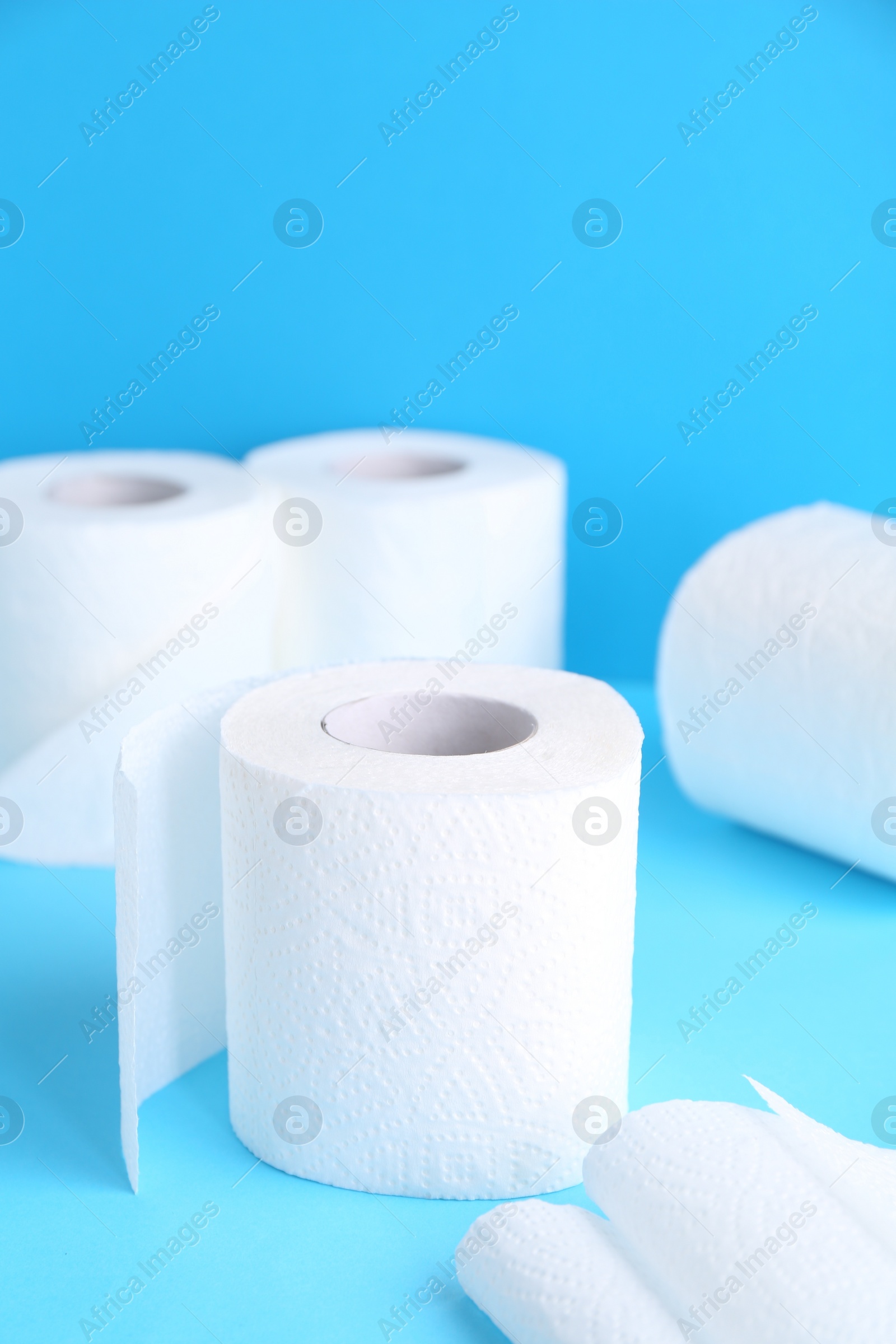 Photo of Soft toilet paper rolls on light blue background