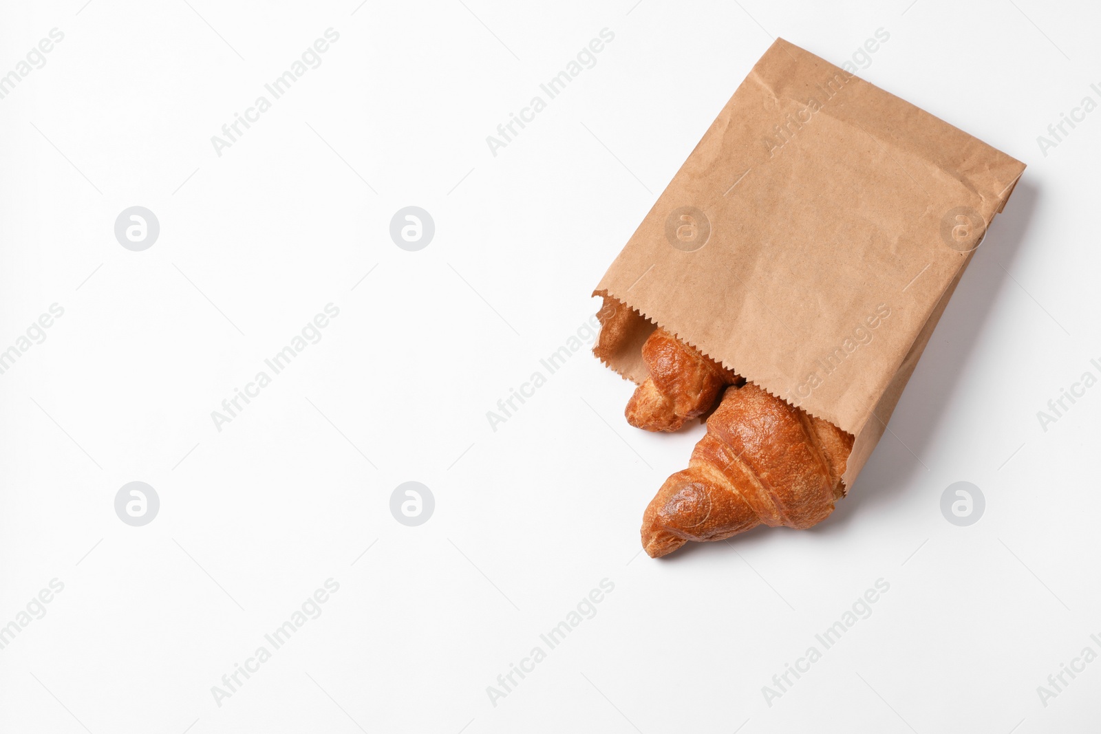 Photo of Paper bag with delicious croissants on white background. Space for text