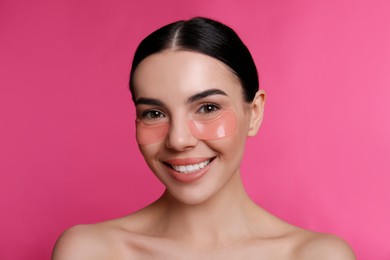 Photo of Beautiful young woman with under eye patches on pink background