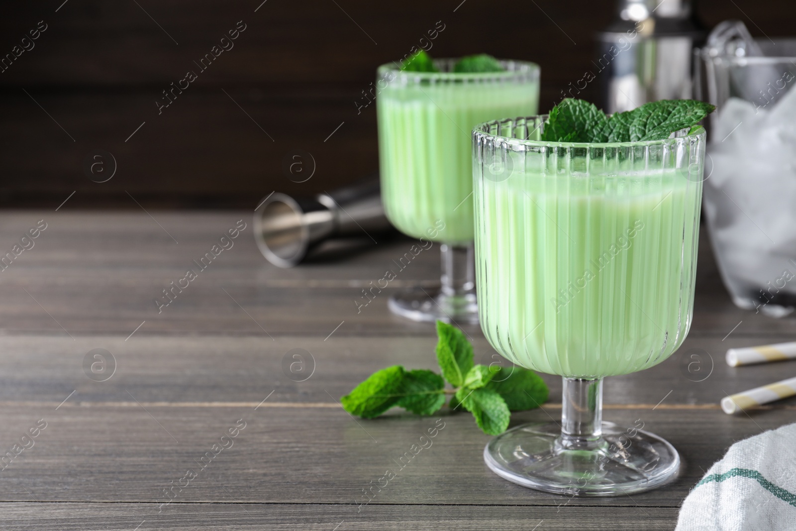 Photo of Delicious mint liqueur with green leaves on grey wooden table. Space for text