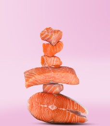 Image of Cut fresh salmon falling on pink gradient background