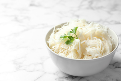 Photo of Tasty fermented cabbage on white marble table, closeup