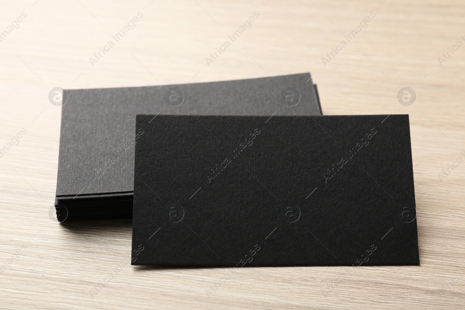 Photo of Blank black business cards on wooden table, closeup. Mockup for design