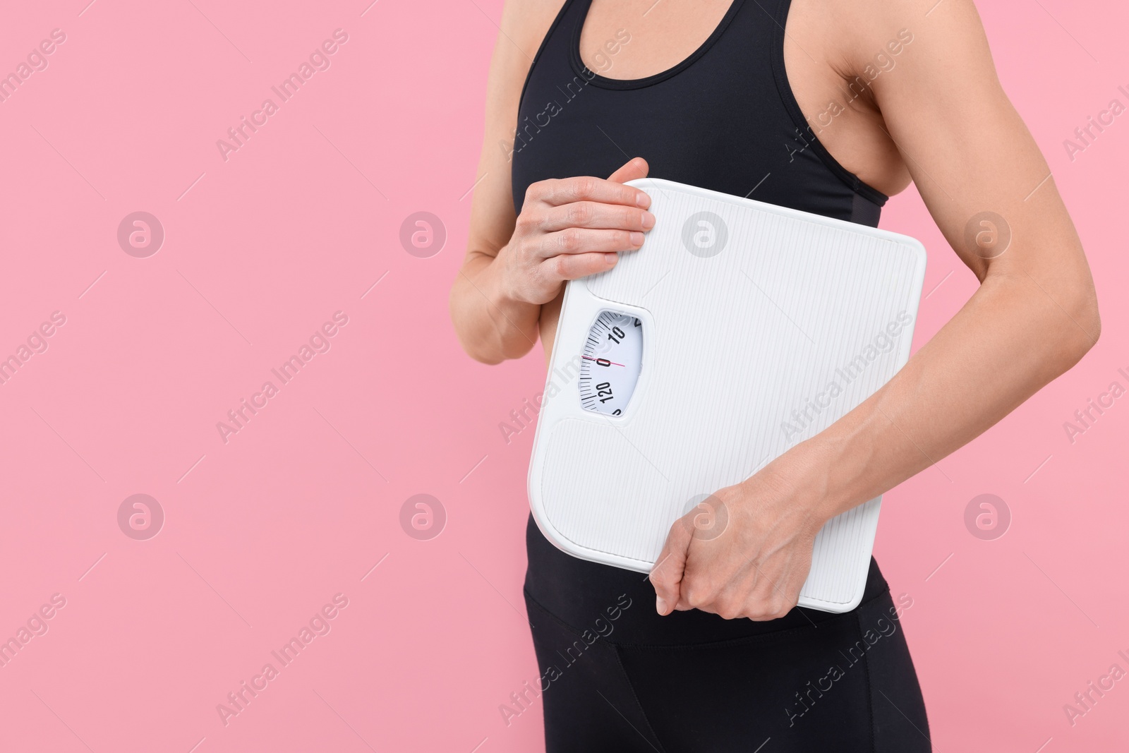 Photo of Slim woman holding scales on pink background, closeup and space for text. Weight loss