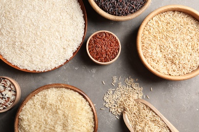 Flat lay composition with brown and other types of rice on grey background