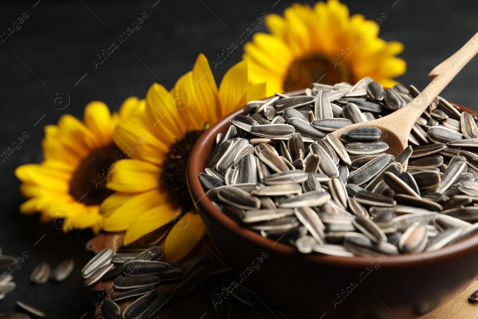 Photo of Raw sunflower seeds and flowers on table, closeup